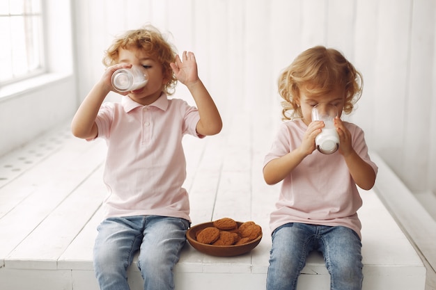 Schattige kinderen eten koekjes en consumptiemelk