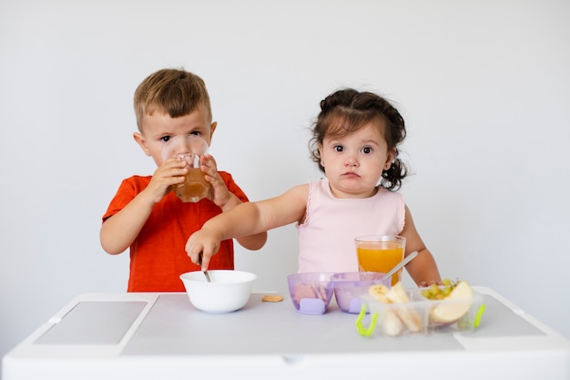 Schattige kinderen zitten en genieten van hun snacks