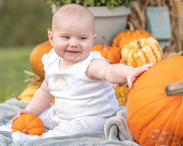 Schattige kleine baby die bij de pompoenen zit met Halloween