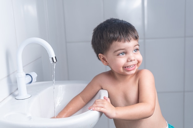 Schattige kleine babyjongen hand wassen in de badkamer wastafel