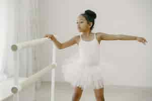 Gratis foto schattige kleine ballerina in roze balletkostuum. het kind in pointe-schoenen danst in de kamer. kid in dansles.