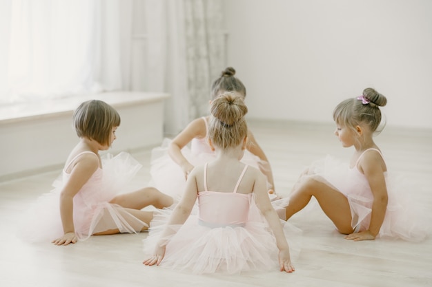 Gratis foto schattige kleine ballerina's in roze balletkostuum. kinderen in spitzen dansen in de kamer. kid in dansles.