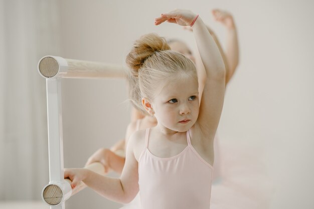 Schattige kleine ballerina's in roze balletkostuum. Kinderen in spitzen dansen in de kamer. Kid in dansles.