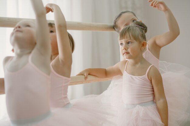 Schattige kleine ballerina's in roze balletkostuum. Kinderen in spitzen dansen in de kamer. Kid in dansles.