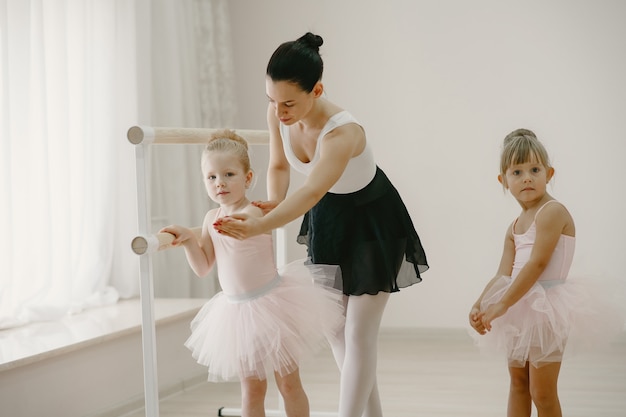 Schattige kleine ballerina's in roze balletkostuum. Kinderen in spitzen dansen in de kamer. Kind in dansles met teatcher.