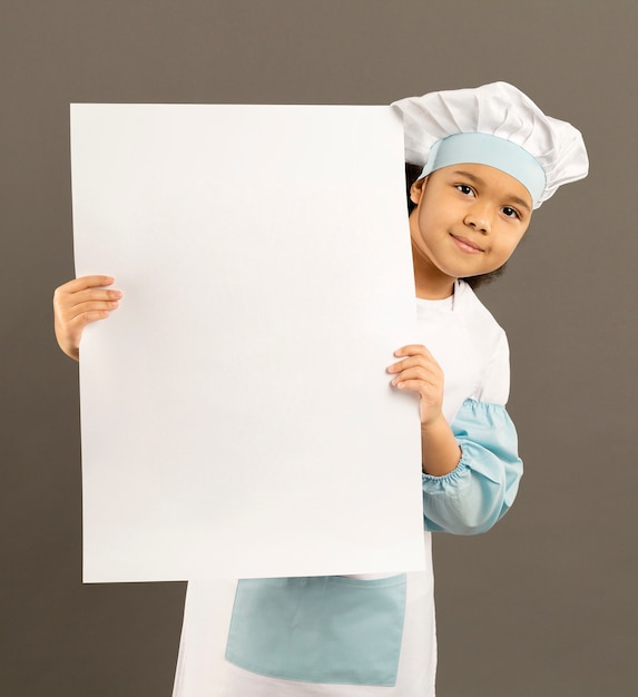 Gratis foto schattige kleine chef-kok met lege banner