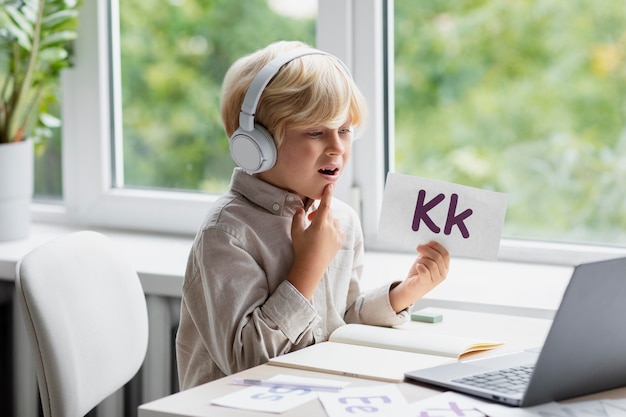 Schattige kleine jongen doet een online sessie logopedie