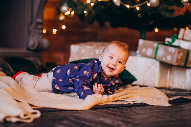 Schattige kleine jongen door de kerstboom