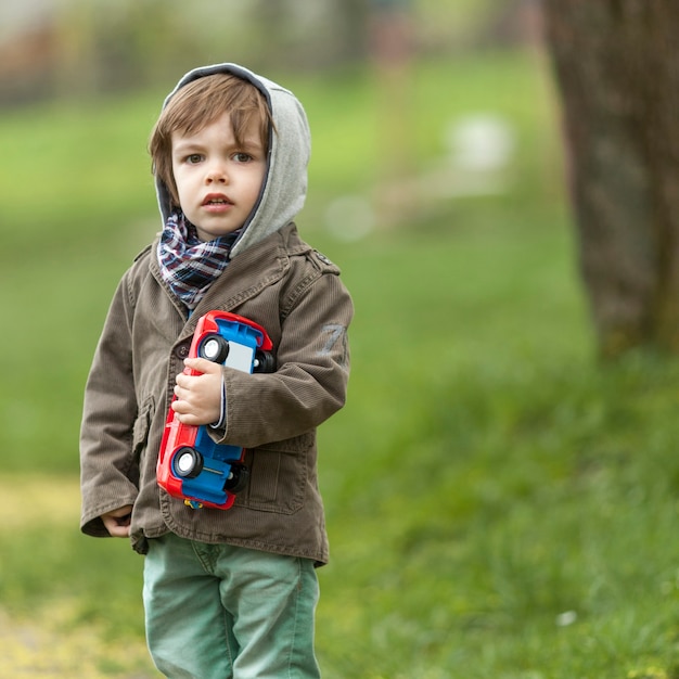 Gratis foto schattige kleine jongen speelgoedauto houden