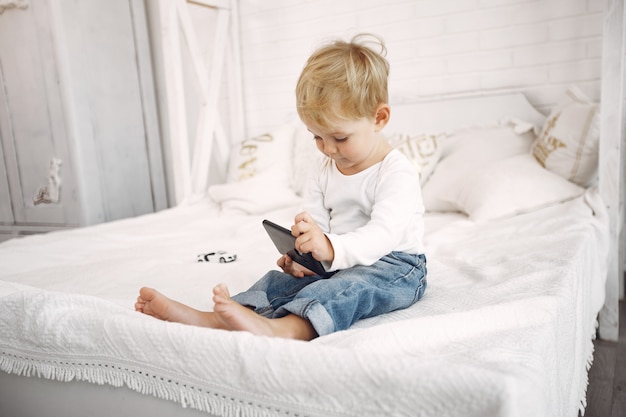 Schattige kleine jongen speelt met een laptop op een bed