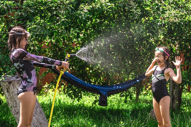 Gratis foto schattige kleine meisjes spelen met een tuinslang op hete zomerdag