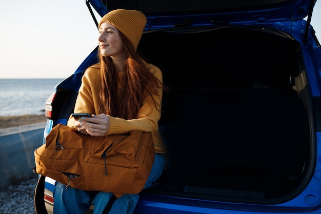 Gratis foto schattige roodharige casual vrouw reist buiten in de auto