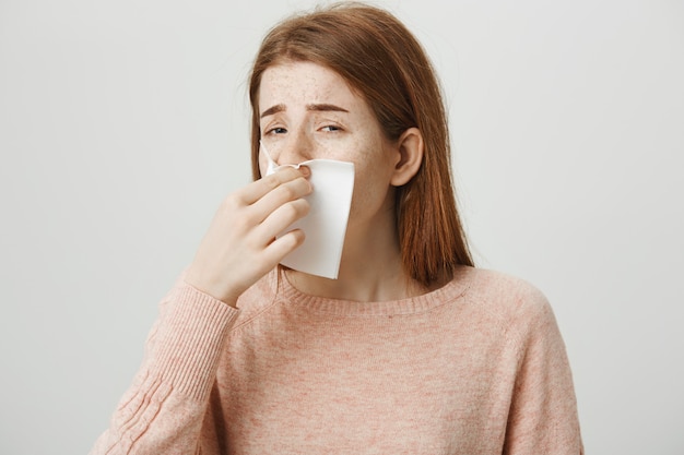 Schattige roodharige meisje met allergie niezen in servet