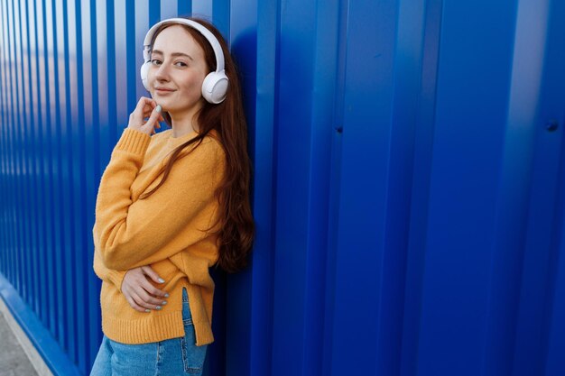 schattige roodharige vrouw luistert naar muziek in een koptelefoon