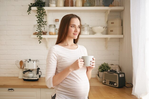 Schattige schattige jonge zwangere vrouw poseren