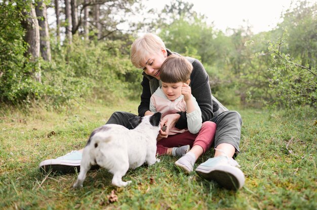 Schattige vrouw en jonge jongen spelen met hond