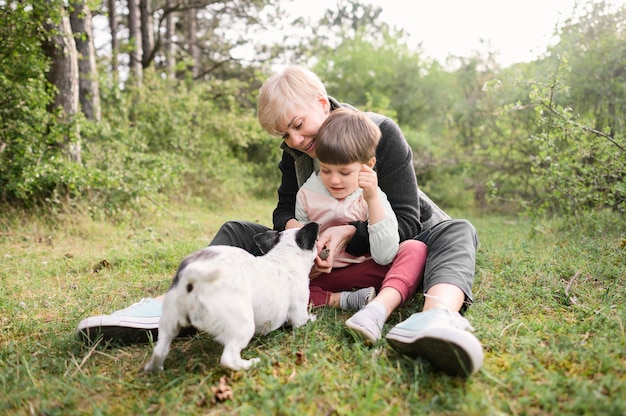 Schattige vrouw en jonge jongen spelen met hond