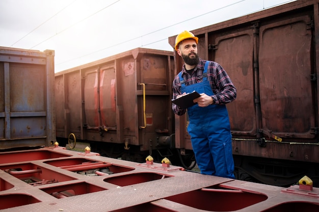 Gratis foto scheepvaartspoorwegarbeider met klembord die vrachtcontainers bijhoudt die klaar zijn om het treinstation te verlaten