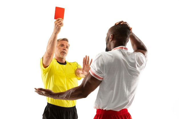 Scheidsrechter die een rode kaart toont aan een ontevreden afro-amerikaanse voetbal- of voetballer tijdens het gamen geïsoleerd op een witte achtergrond.