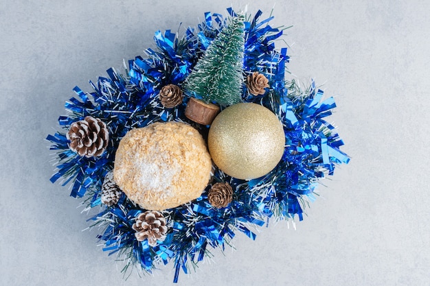 Schilferige cake genest op een bundel kerstversieringen op een marmeren oppervlak