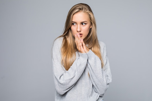 Schitterende jonge brunette vrouw in warme gebreide trui geïsoleerd op een grijze achtergrond