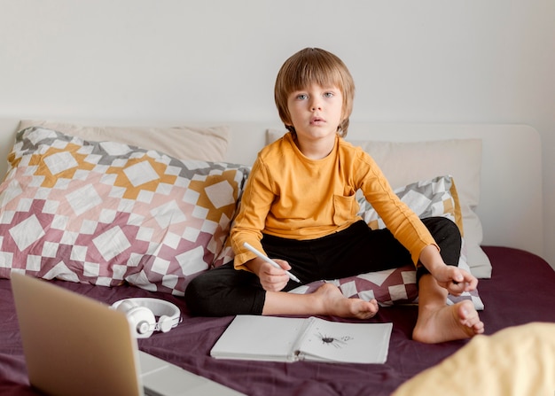 School jongen zittend in bed vooraanzicht