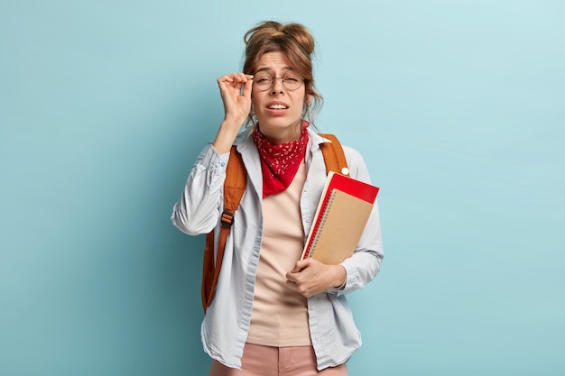 Schoolgril met slecht zicht probeert in de verte iets te zien, houdt zijn hand op brilmontuur