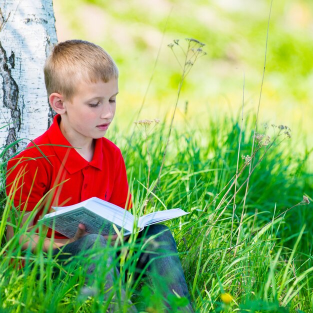 Gratis foto schooljongen die het boek leest bij aard