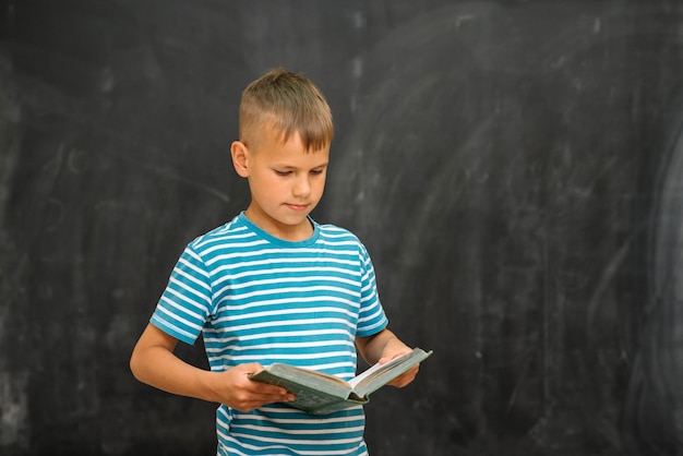 Gratis foto schooljongen met boek op schoolbord