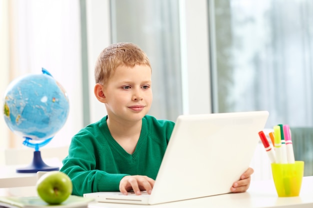 Schooljongen met een laptop op zijn bureau