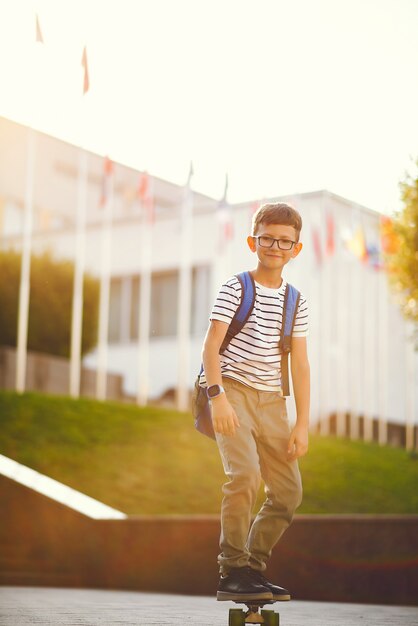 Schooljongen met een skate en rugzak