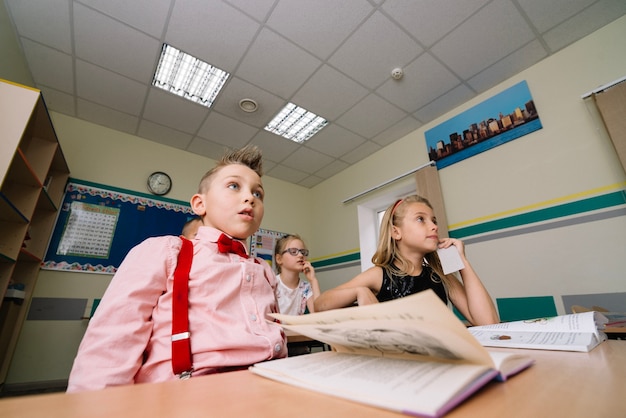 Schoolkinderen aan de tafel zitten met handboeken