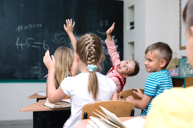 Schoolkinderen zitten in klaslokaal handen verhogen