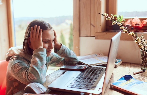 Gratis foto schoolmeisje huiswerk thuis en kijkt bezorgd