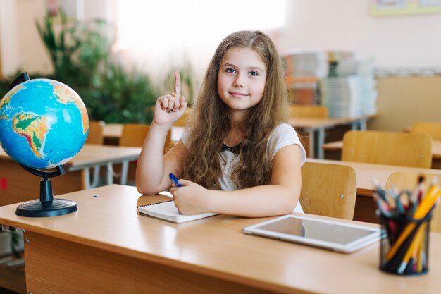 Schoolmeisje in de klas wijzen op