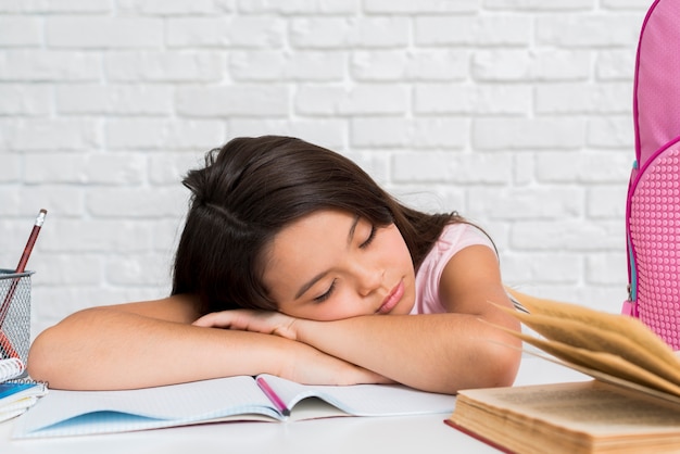 Schoolmeisje in slaap met hoofd op voorbeeldenboek