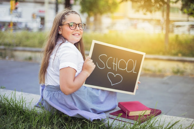 Gratis foto schoolmeisje in uniform met teken school liefde