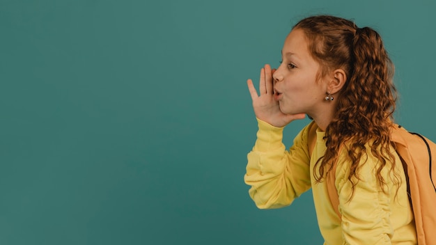 Gratis foto schoolmeisje met geel overhemd dat een geheim vertelt