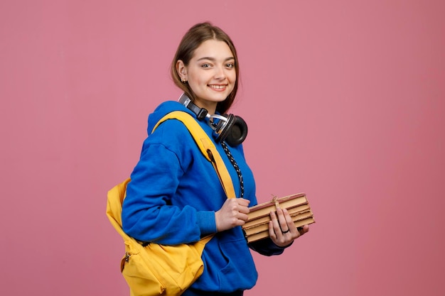 Schoolmeisje met koptelefoon op nek staande glimlachend