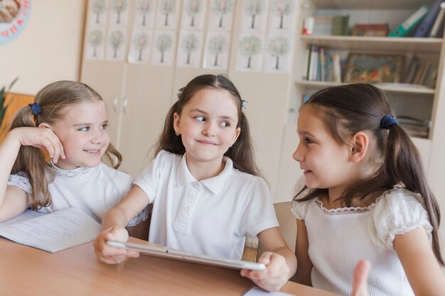 Schoolmeisjes met tablet die met elkaar spreken