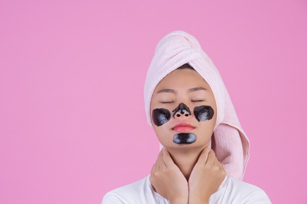 Schoonheid cosmetische peeling. Jonge vrouw met zwarte peeling masker op huid cosmetische huidverzorging peeling product op het gezicht op een roze.
