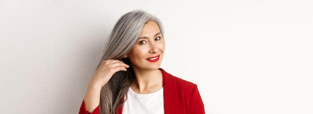 Gratis foto schoonheid en haarverzorgingsconcept close-up van elegante aziatische senior vrouw die glanzend en gezond grijs haar toont