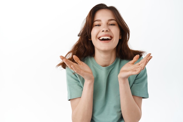 Schoonheid en huidverzorging Mooi tienermeisje met natuurlijke naakte make-up die lacht en een openhartige, mooie glimlach toont die zorgeloos tegen een witte achtergrond staat