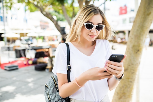 Schoonheid jonge vrouw met behulp van slimme telefoon buiten in de zonnige zomer straat