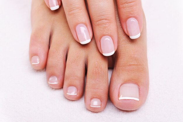 Schoonheid nagels concept van een vrouwelijke hand en voeten met prachtige Franse manicure en pedicure