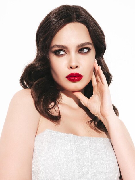 Schoonheid portret van jonge brunette vrouw met avond make-up en perfecte schone huid Sexy model met krullend haar poseren in studio met rode heldere natuurlijke lippen In zilveren jurk
