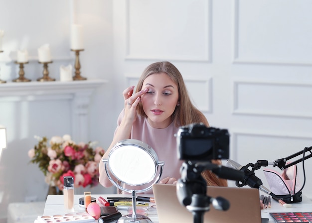 Gratis foto schoonheid vlogger. jonge vrouw die een make-uptutorial opneemt