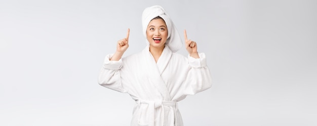 Schoonheidsportret van een jonge vrouw die met de vinger wijst naar lege kopieerruimte Aziatische schoonheid in badjas
