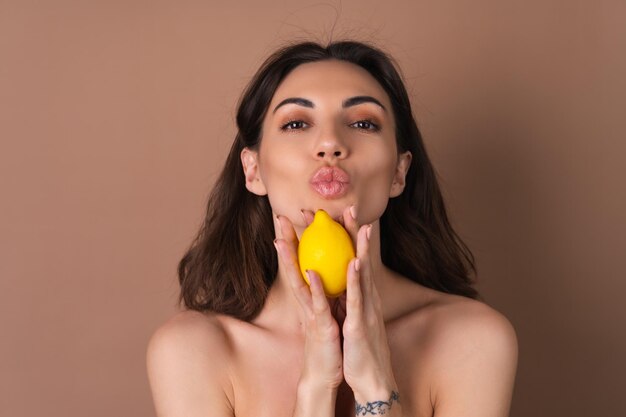 Schoonheidsportret van topless vrouw met perfecte huid en natuurlijke make-up op een beige achtergrond bevat citrus-citroenvitamines c voor de huid