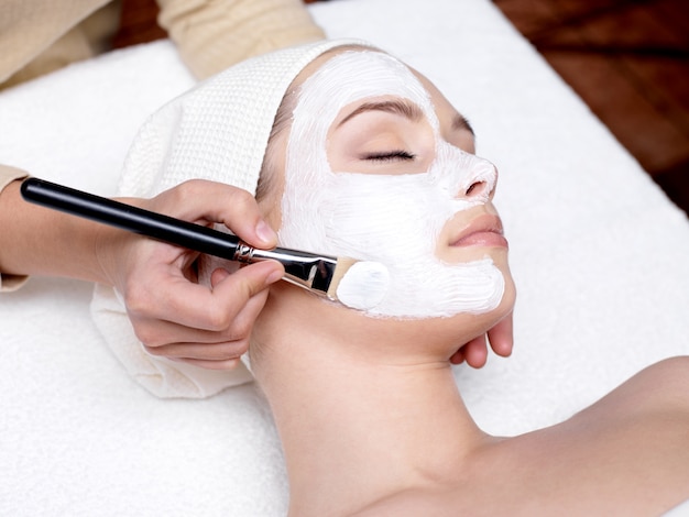 Schoonheidsspecialist gezicht schoonheid masker toe te passen voor jonge mooie vrouw op spa salon